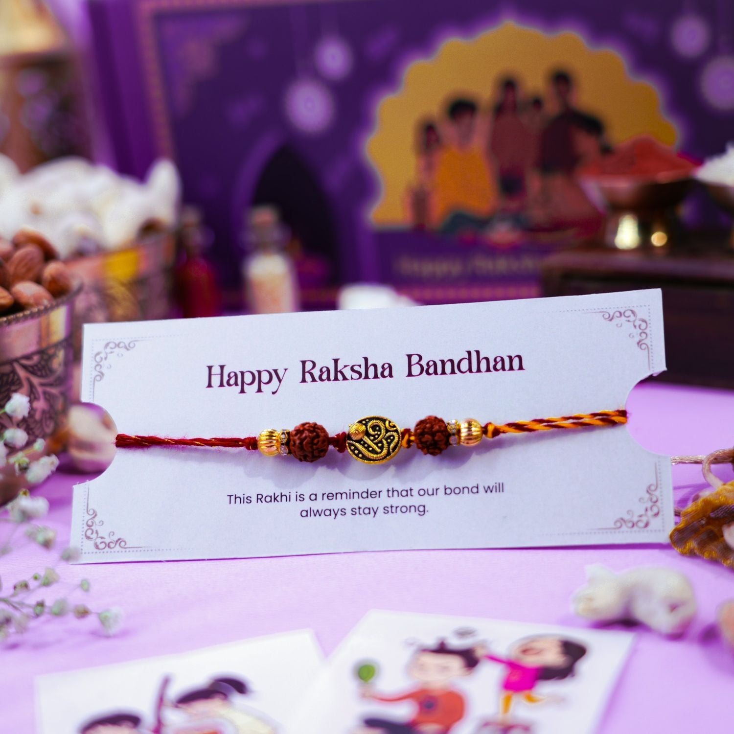 Rudraksha rakhi with Om charm placed on Raksha Bandhan greeting card and festive items.