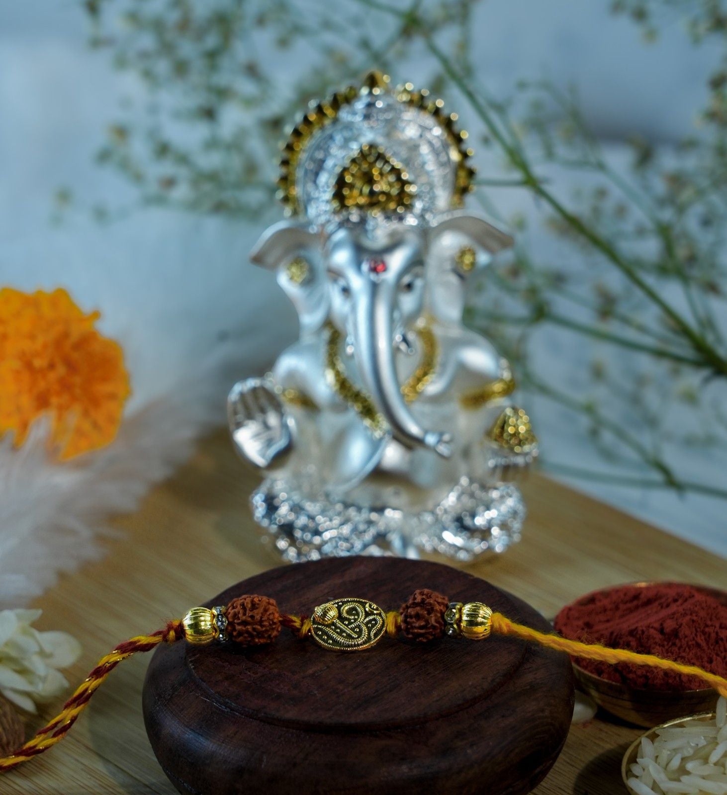 Rudraksha Rakhi with Om design placed before silver gold Ganesha idol for Raksha Bandhan.