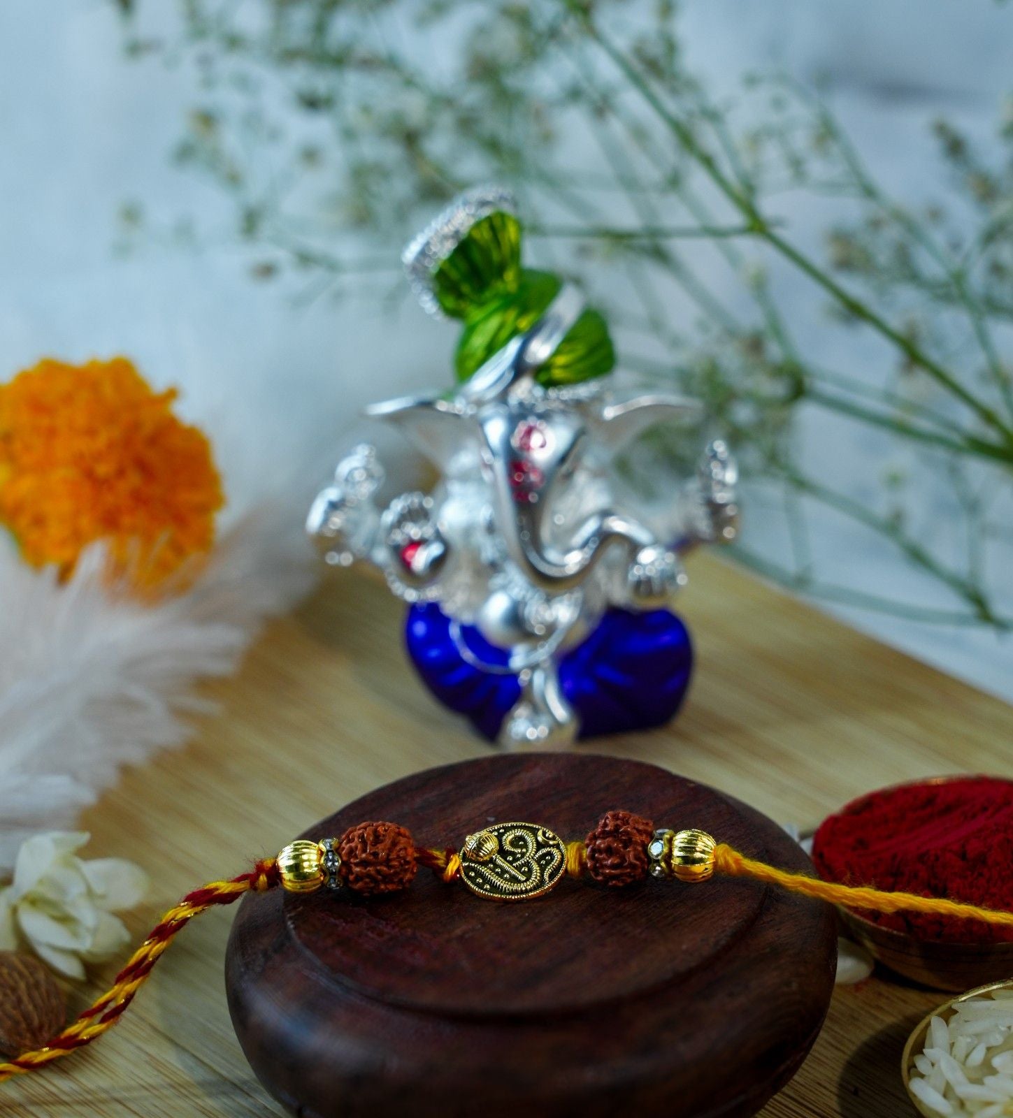 Rudraksha Rakhi with Om design and Pagdi Ganesha idol for Raksha Bandhan ritual gift.