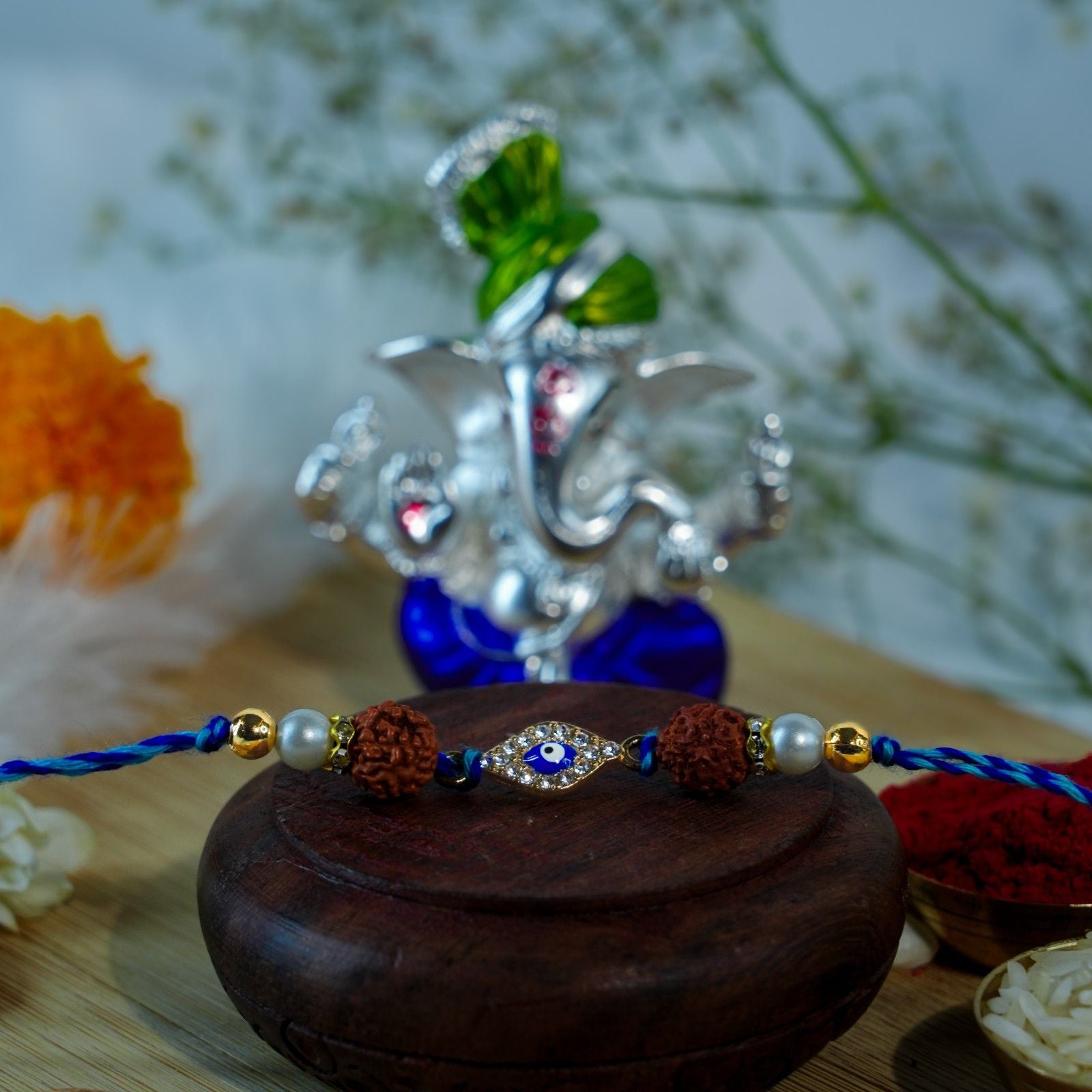 Spiritual Raksha Bandhan Rakhi with Rudraksha and Evil Eye beside Pagdi Ganesha idol.